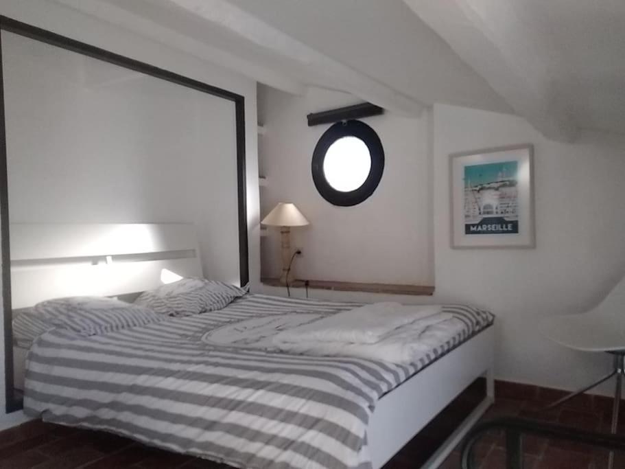 a bedroom with a bed and a round window at STUDIO PORT MIOU terrasse proximité mer - Calanques in Marseille
