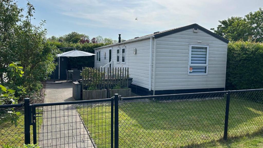 ein kleines Haus in einem Hof mit einem Zaun in der Unterkunft RBR 211 - Beach Resort Kamperland in Kamperland
