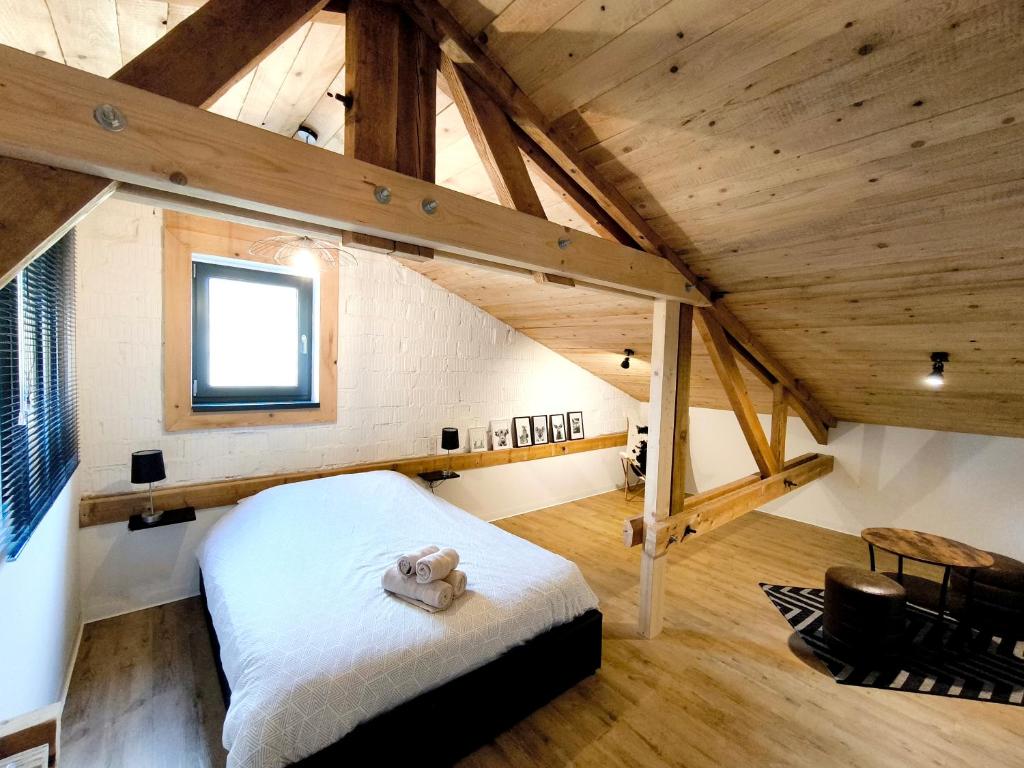 a room with a bed in a loft with wooden ceilings at Cocon de caractère au cœur des vignes Alsaciennes in Bergheim