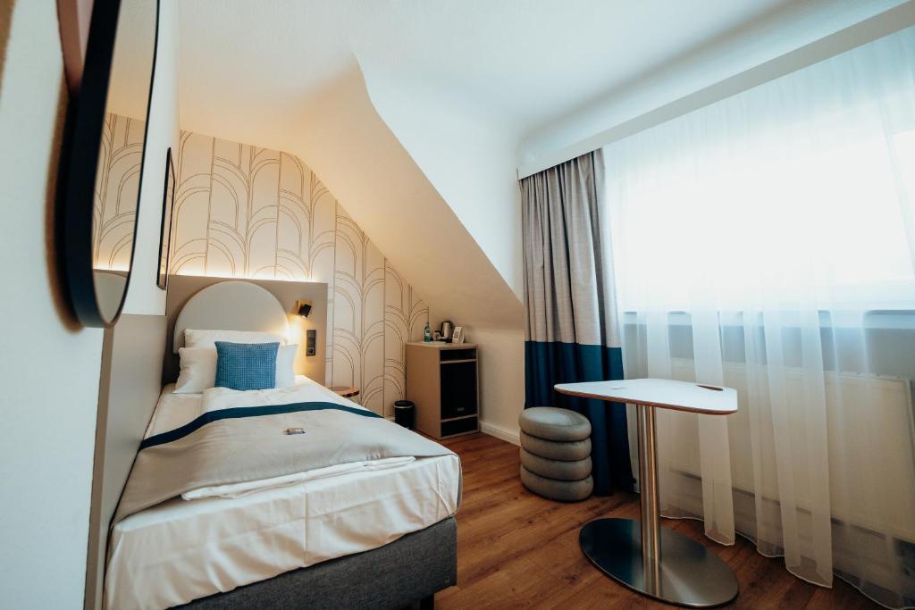 a bedroom with a bed and a table in it at guestified LIYANA in Ratingen