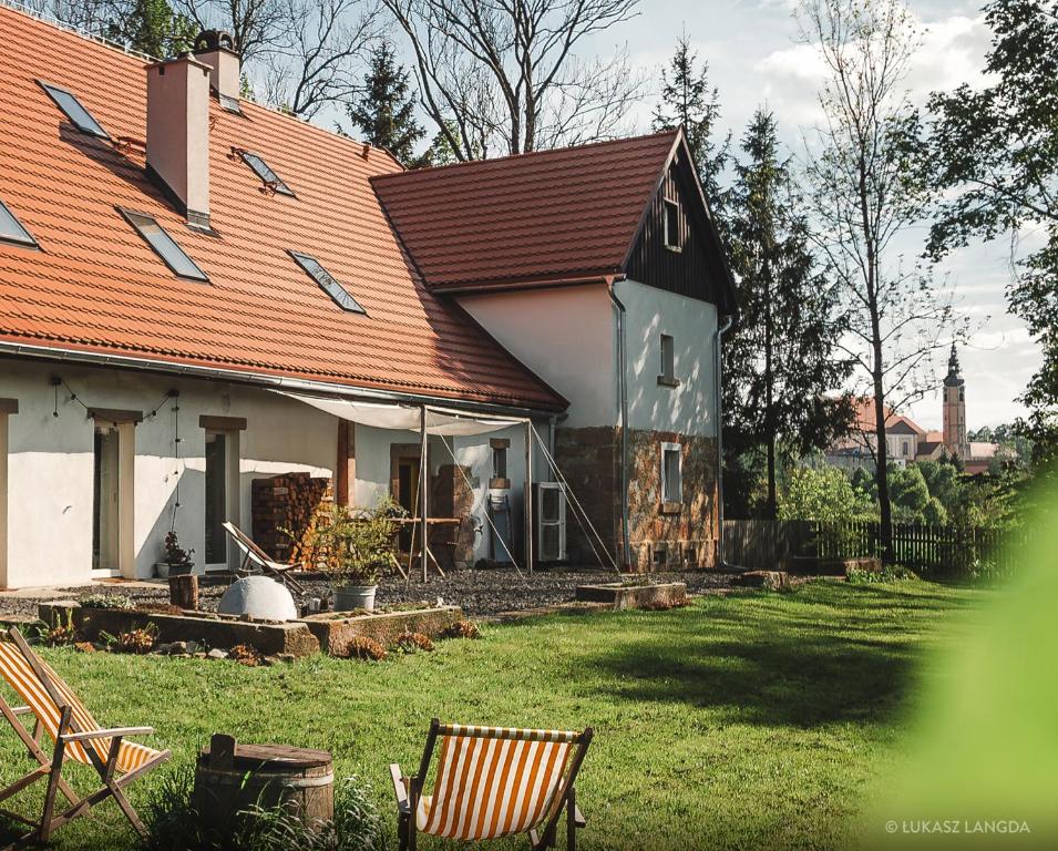 una casa con tetto rosso e un cortile con sedie di Wietorówka a Lubomierz