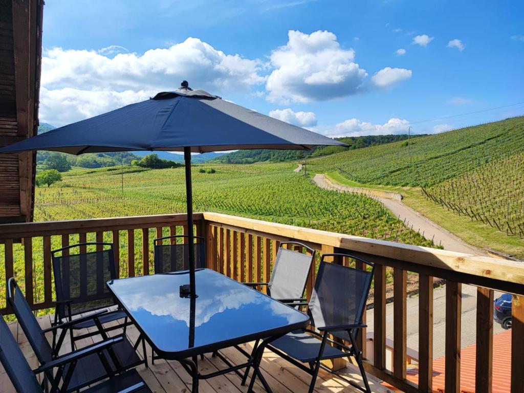 a table and chairs on a deck with an umbrella at L'Horizon in Bergheim