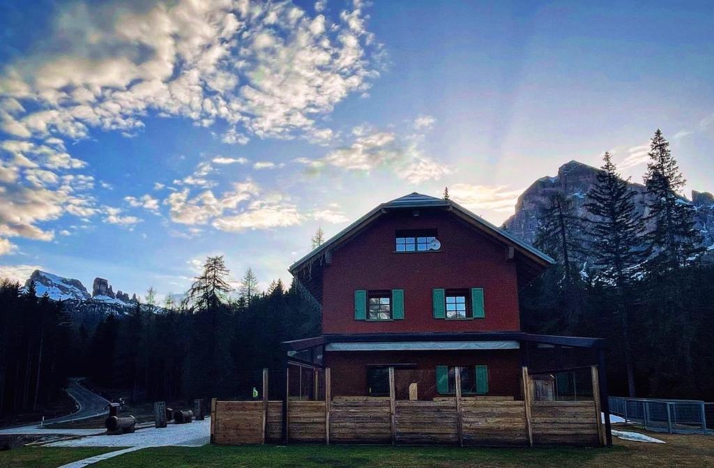 una gran casa roja con montañas en el fondo en Ciasa Vervei, en Cortina dʼAmpezzo