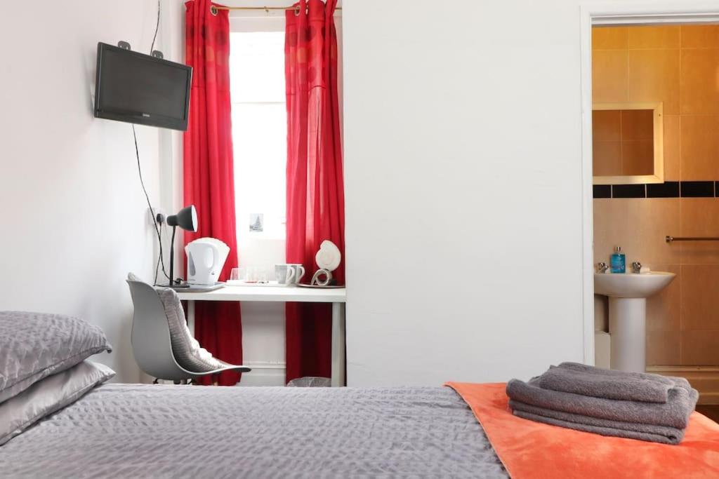 a bedroom with a bed and a desk and a sink at Pebbles guest house in Southampton