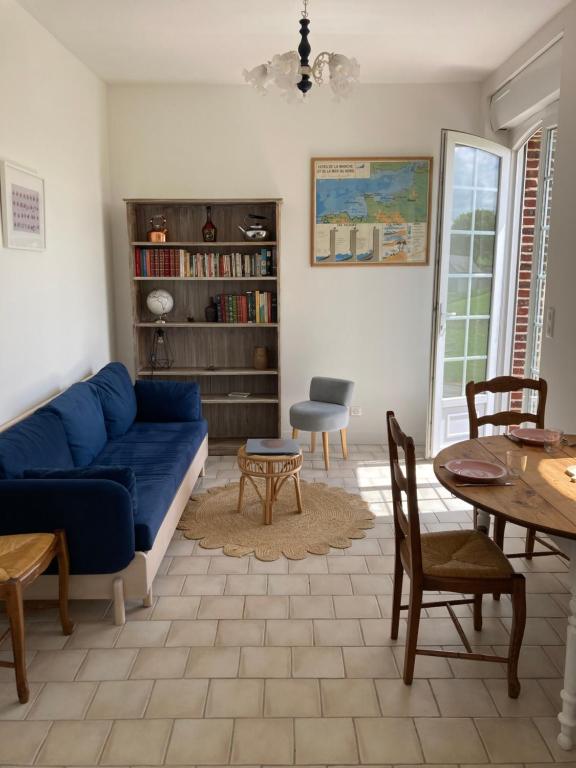 een woonkamer met een blauwe bank en een tafel bij Clos Phitarra, charmant gîte pour 2 personnes à 7 mns d'Etretat in Les Loges