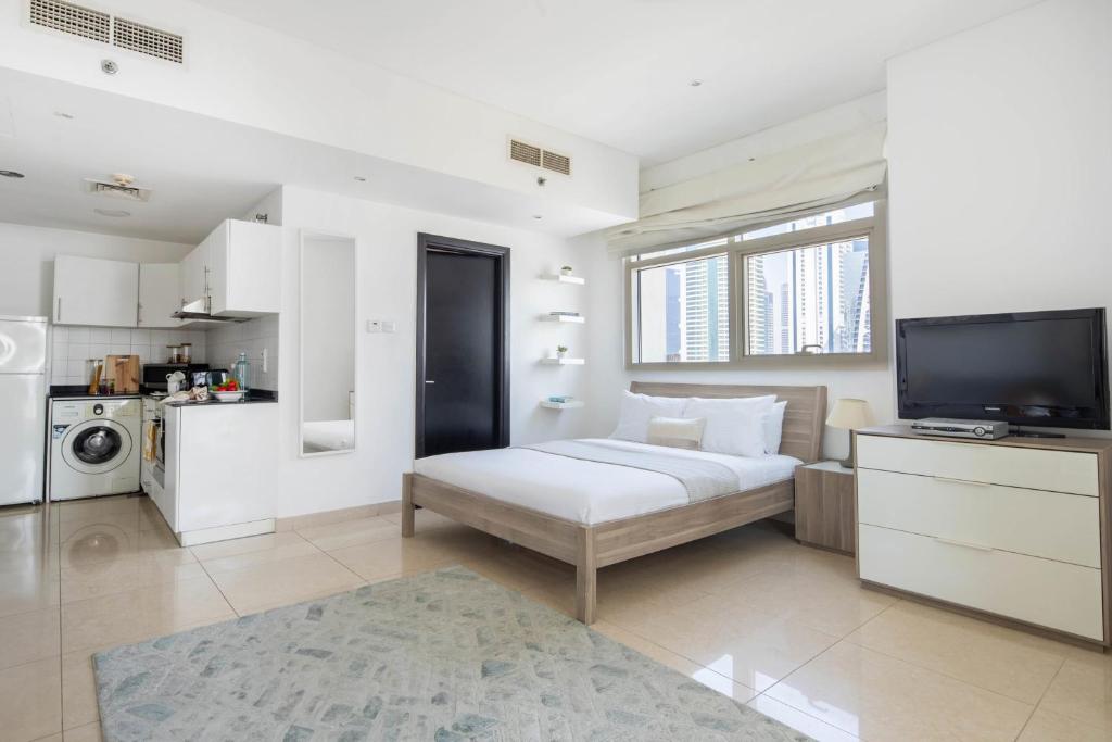 een witte kamer met een bed en een televisie bij Frank Porter - Yach Bay in Dubai
