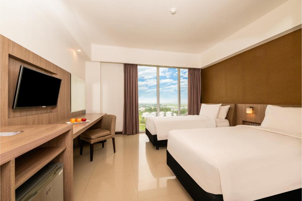 um quarto de hotel com duas camas e uma televisão em ASTON Banua Banjarmasin Hotel & Convention Center em Banjarmasin