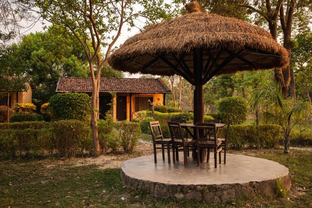 una mesa y sillas bajo una sombrilla grande en Bardia Riverside View Park Resort, en Bhurkīā