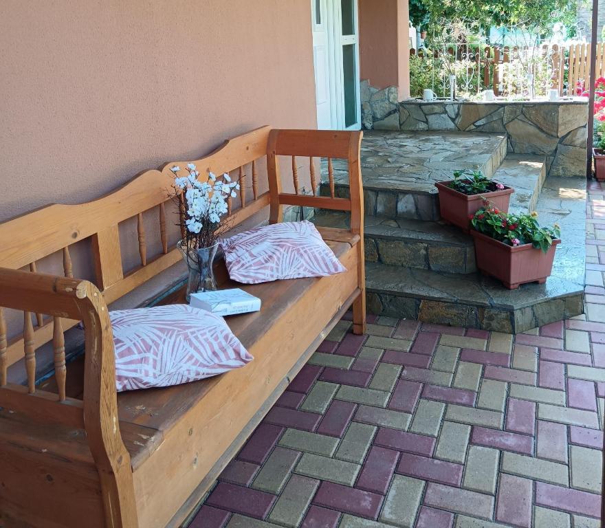 un banco de madera con un jarrón de flores en el patio en Hársfa apartman en Makó