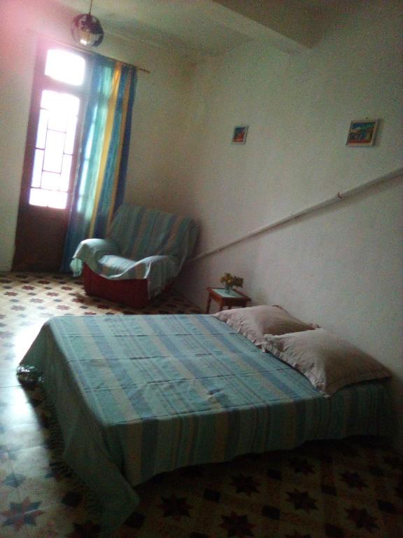 une chambre avec un lit, une chaise et une fenêtre dans l'établissement Ancien café des années 30, à Bélesta