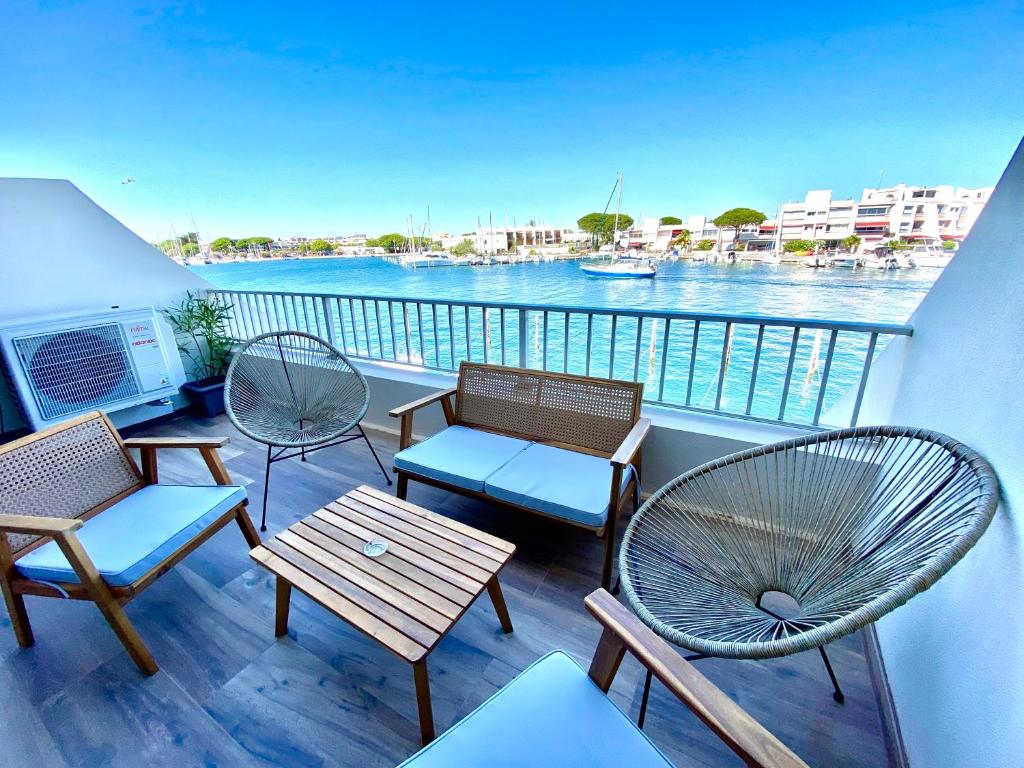 balcón con sillas, mesas y vistas al agua en Marina appartement sur l’eau, en Le Grau-du-Roi