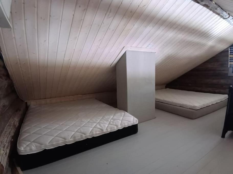 two beds in a room with a ceiling at Cottage by the Muonio river for 6 person in Kolari
