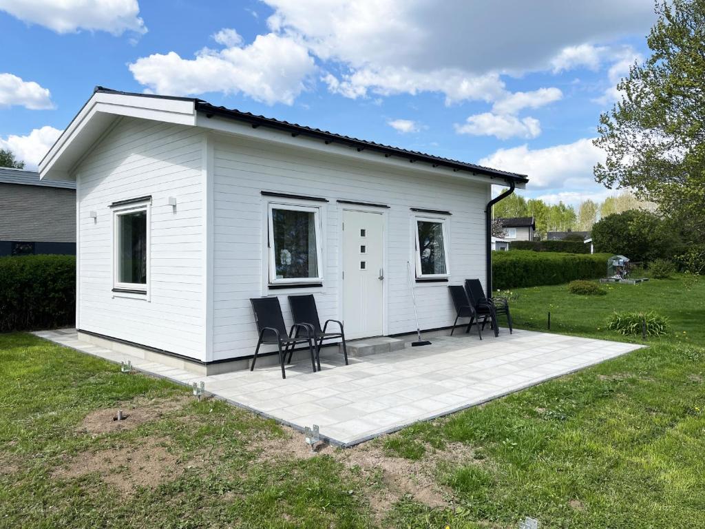 una piccola casa bianca con sedie in cortile di Newly built guest house located in Vimmerby a Vimmerby