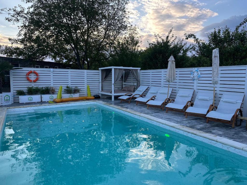 uma piscina com cadeiras ao lado de uma cerca em La Căsuțe em Silvaşu de Jos