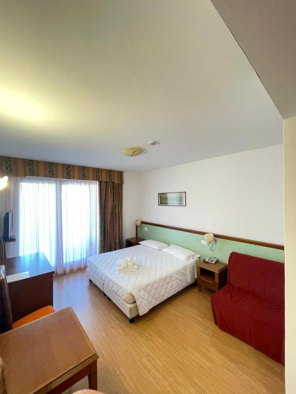 una camera d'albergo con un letto e un divano rosso di Hotel Il Guscio a Grado