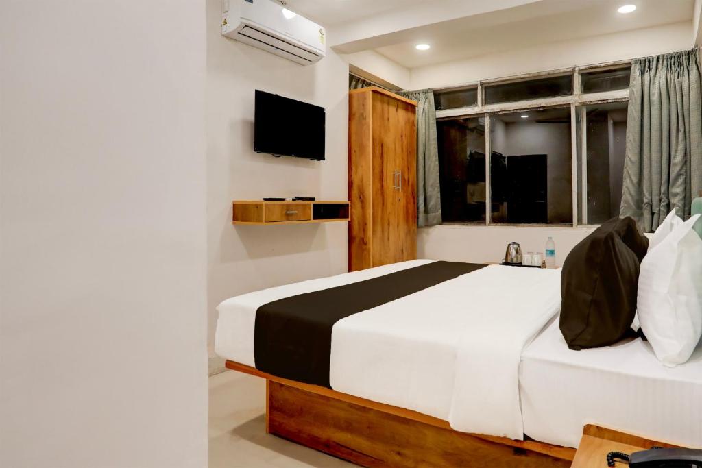 um quarto com uma cama, uma janela e uma televisão em OYO HOTEL R CK INN em Rajkot