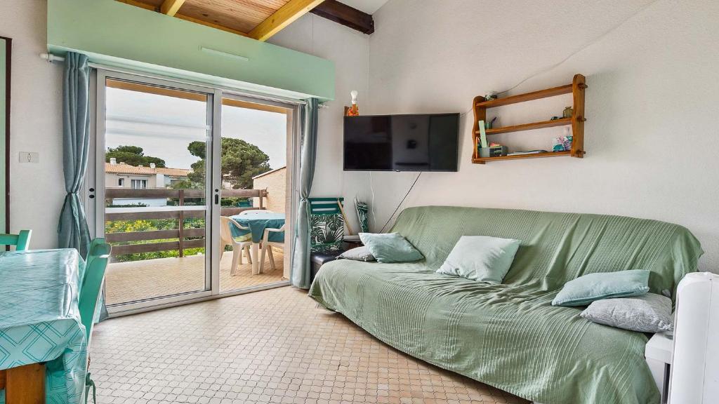 Il comprend un salon avec un canapé vert et un balcon. dans l'établissement IPANEMA - 181 - Studio Mezzanine 4-6 pers, au Cap d'Agde