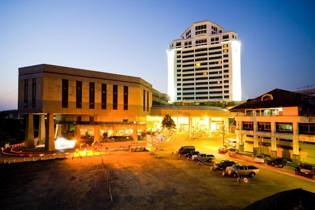 un grupo de edificios con coches estacionados en un estacionamiento en Thumrin Thana Hotel, en Trang