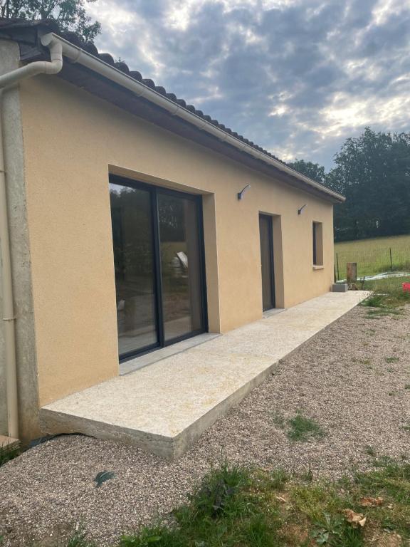 une petite maison avec une grande porte en verre dans l'établissement Bienvenue dans la maison du Ch’ti du Périgord noir, à Audrix