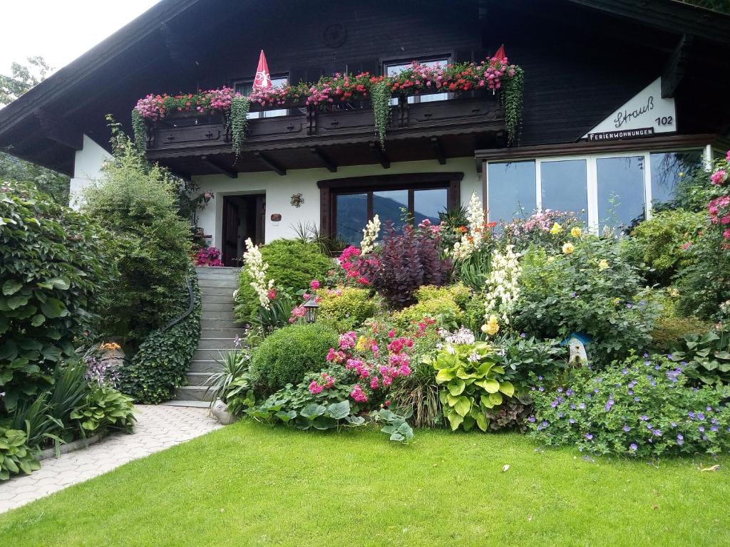a house with a bunch of flowers in the yard at Blumenpension Strauss - Ferienwohnungen in Ossiach