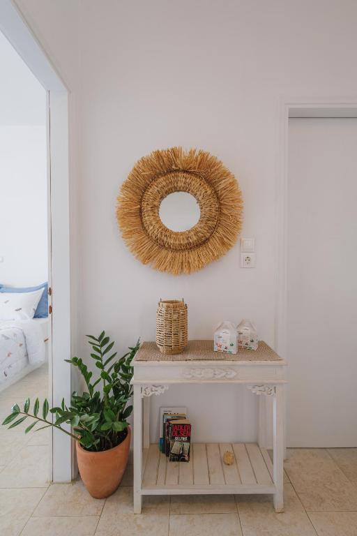 a white console table with a mirror and a plant at Studios Eliza in Livadi