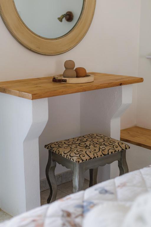 a mirror and a stool on a shelf with a stool at Studios Eliza in Livadi