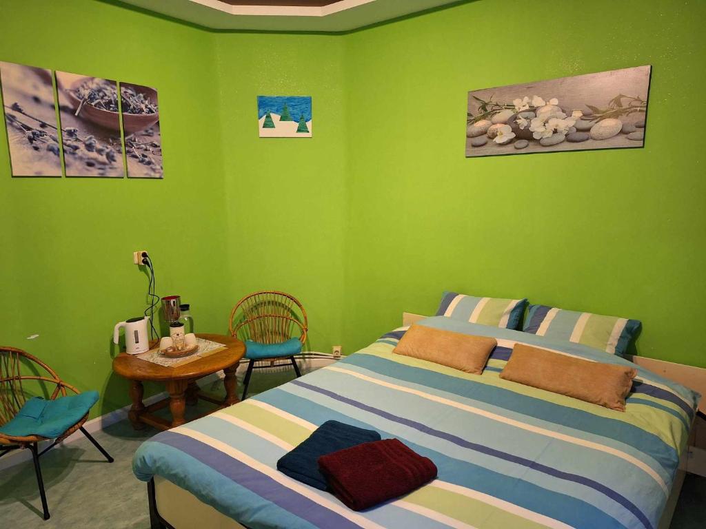 Simpele slaapkamer Geraardsbergen في جيرادسبرجن: غرفة نوم خضراء بسرير وطاولة وكراسي