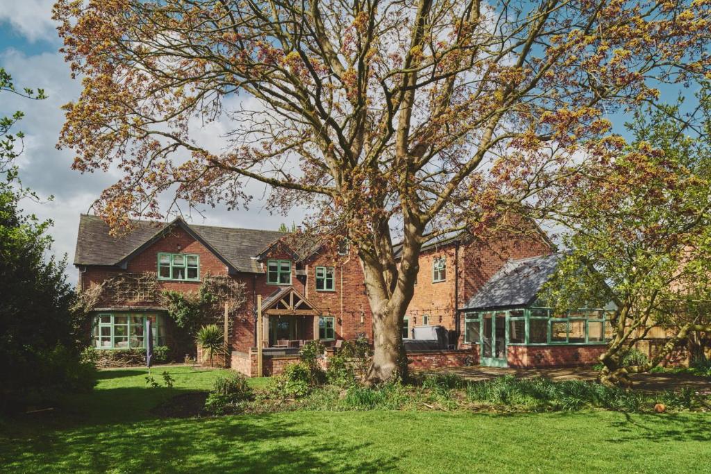 a large brick house with a tree in the yard at Sandy Hill Farm in Curborough