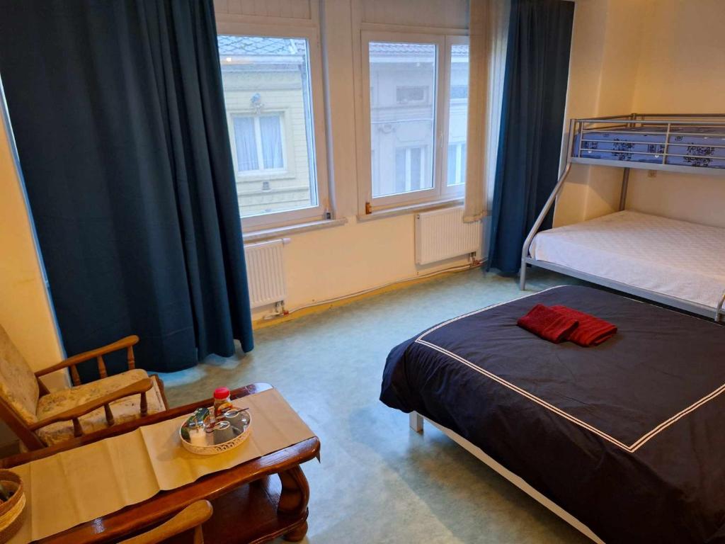 1 dormitorio con 1 cama, 1 mesa y 2 ventanas en Slaapkamer markt Geraardsbergen, en Geraardsbergen