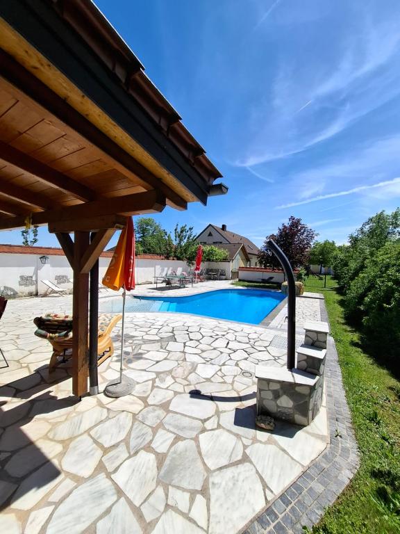 eine Steinterrasse mit Swimmingpool und Sonnenschirm in der Unterkunft Frühstückspension Wahl in Ruprechtshofen