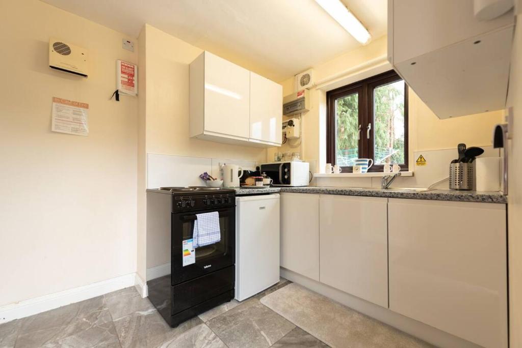 a kitchen with white cabinets and a black oven at Pass the Keys The White House Holiday Cottage in Highley
