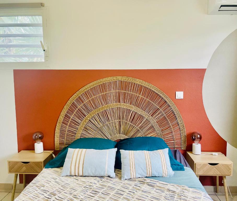 a bed with a large wooden headboard and two tables at Bahia Garden -T2 Proche Université, Netflix, Fibre in Cayenne