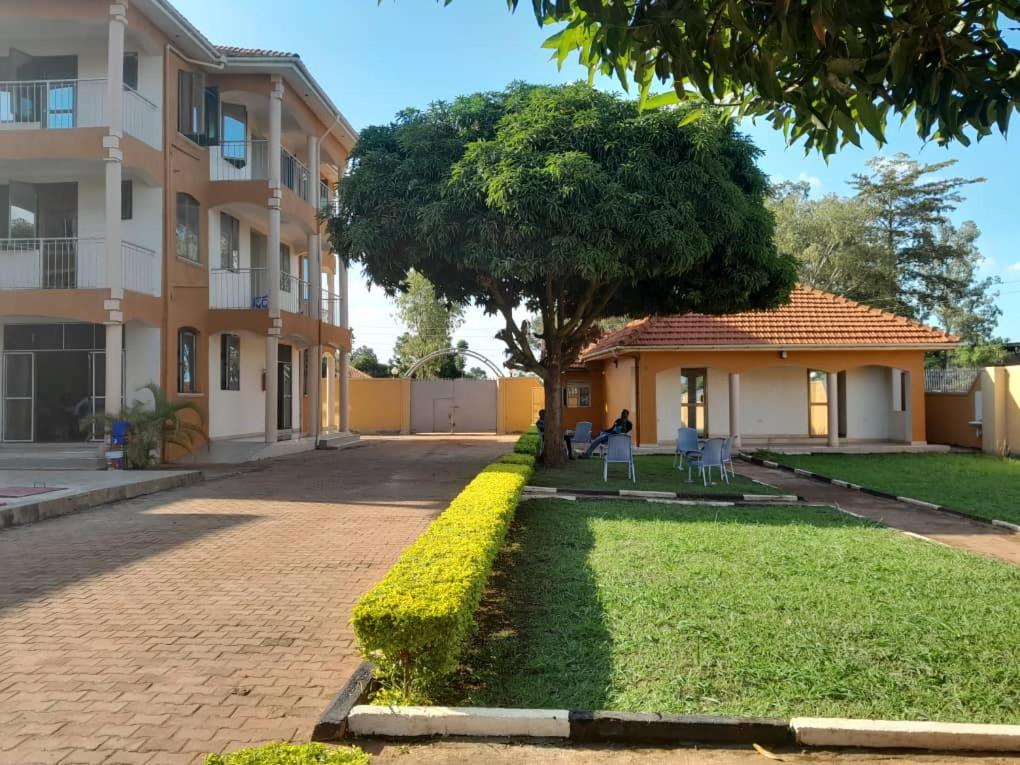 a house with a tree and a brick driveway at Fresh World Hotel in Lira