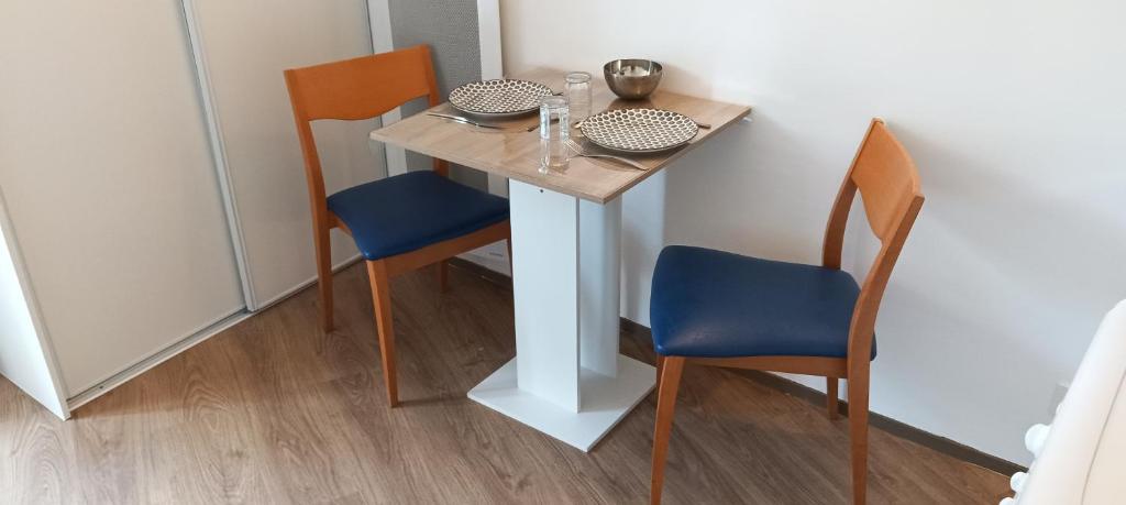 une petite table avec deux chaises et une table avec un siège bleu dans l'établissement Cosy Studio La Defense, à Courbevoie