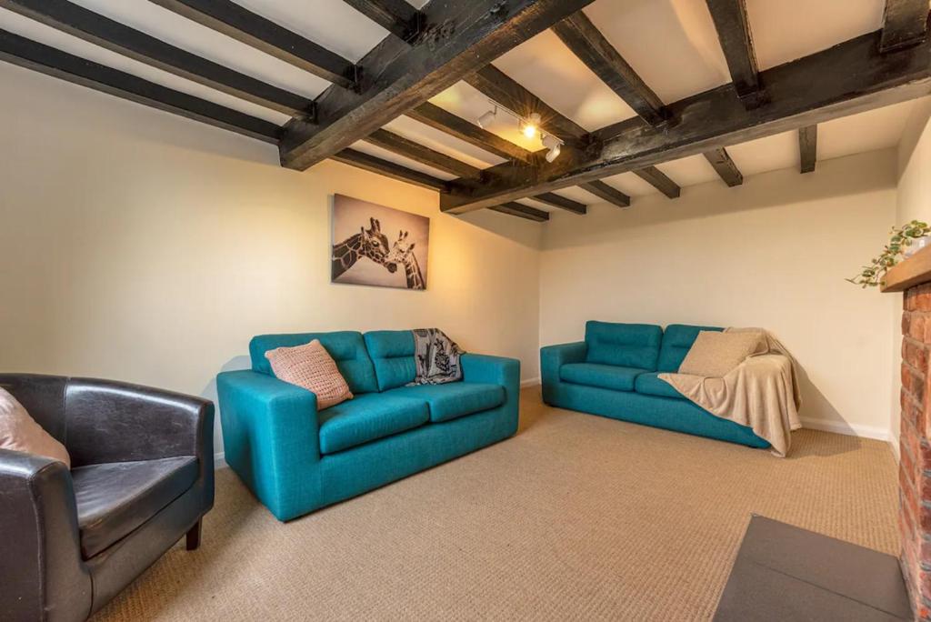 - un salon avec deux canapés bleus et un canapé dans l'établissement Pass the Keys Charming Cottage Stunning Views, à Cheswardine