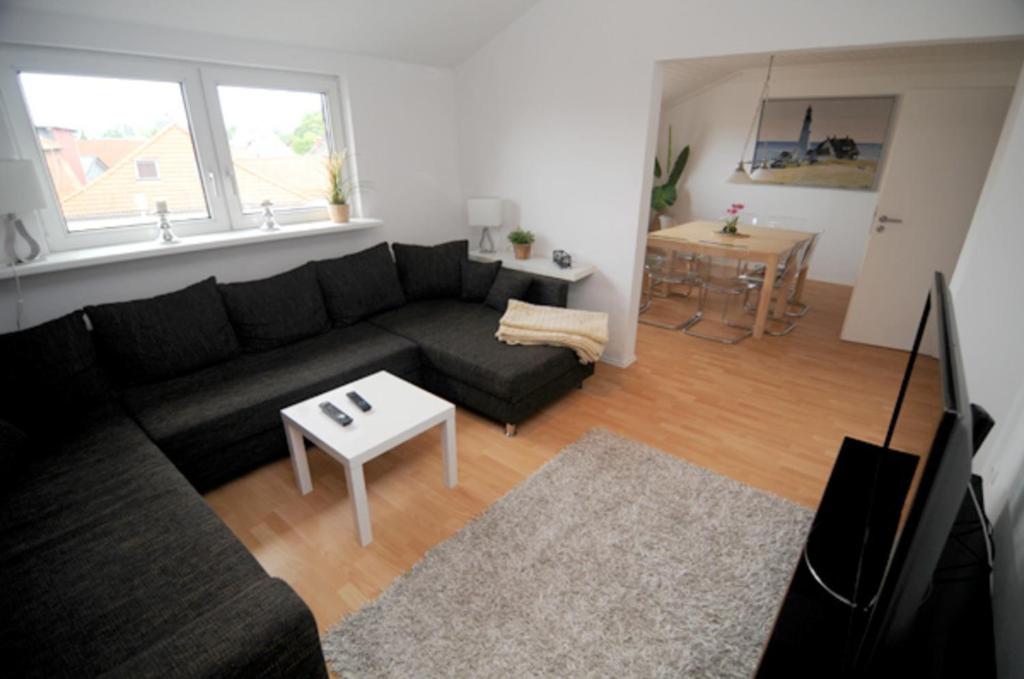 a living room with a black couch and a table at Ferienwohnung Nr 3 in Wunstorf
