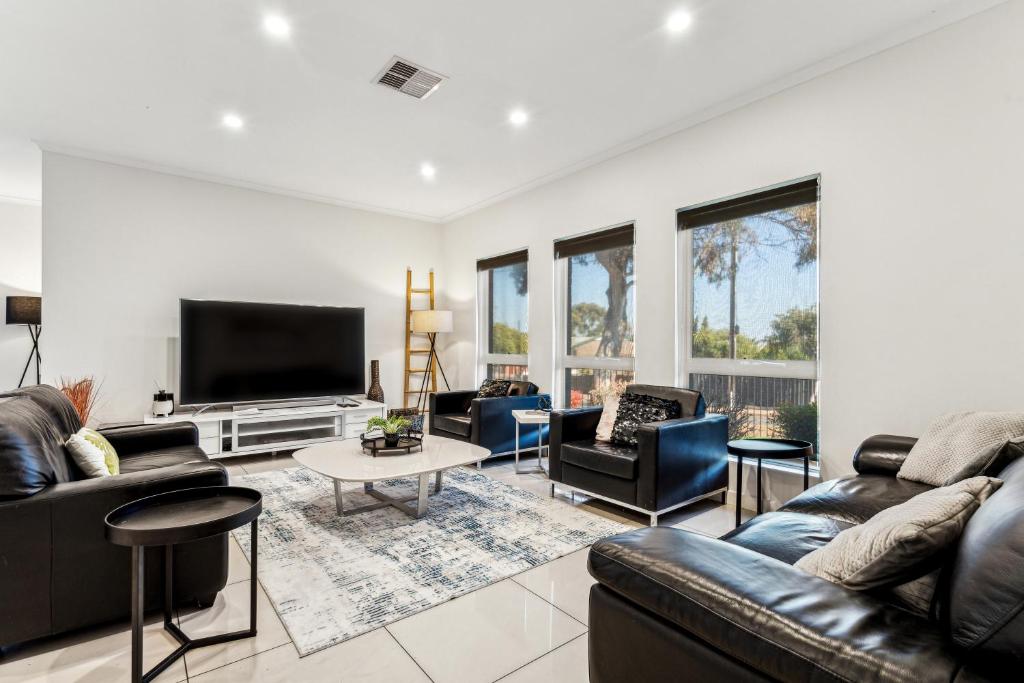 a living room with leather furniture and a flat screen tv at Enfield Executive in Gepps Cross