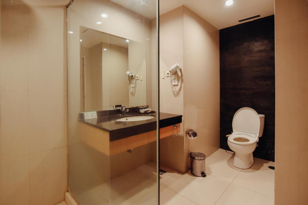 a bathroom with a sink and a toilet at Surabaya Suites Hotel Powered by Archipelago in Surabaya