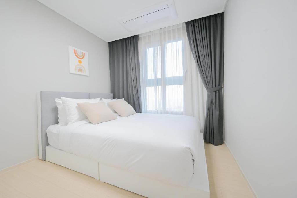 una camera da letto bianca con un letto bianco e una finestra di E7 YANGYANG JUKDO a Yangyang