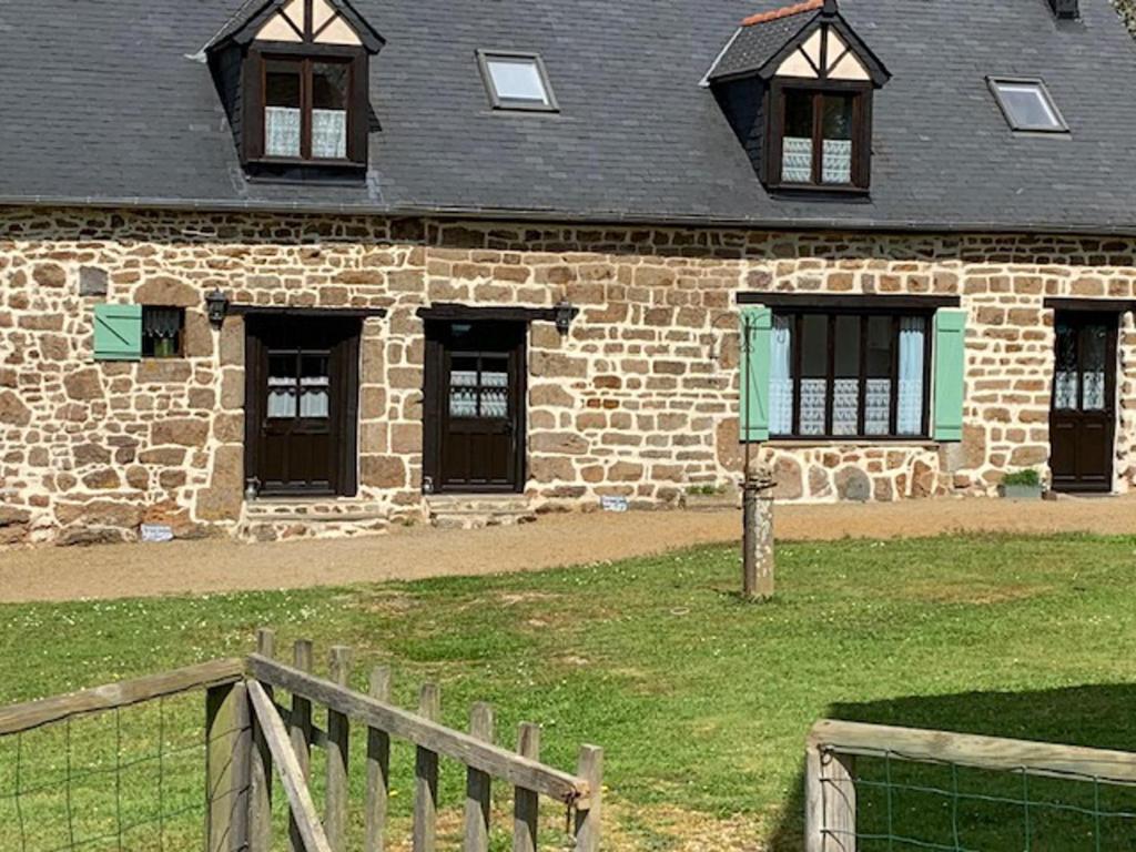 un bâtiment en briques avec des fenêtres et une clôture en bois dans l'établissement Delightful 1-Bed Cottage in Ceauce, à Céaucé
