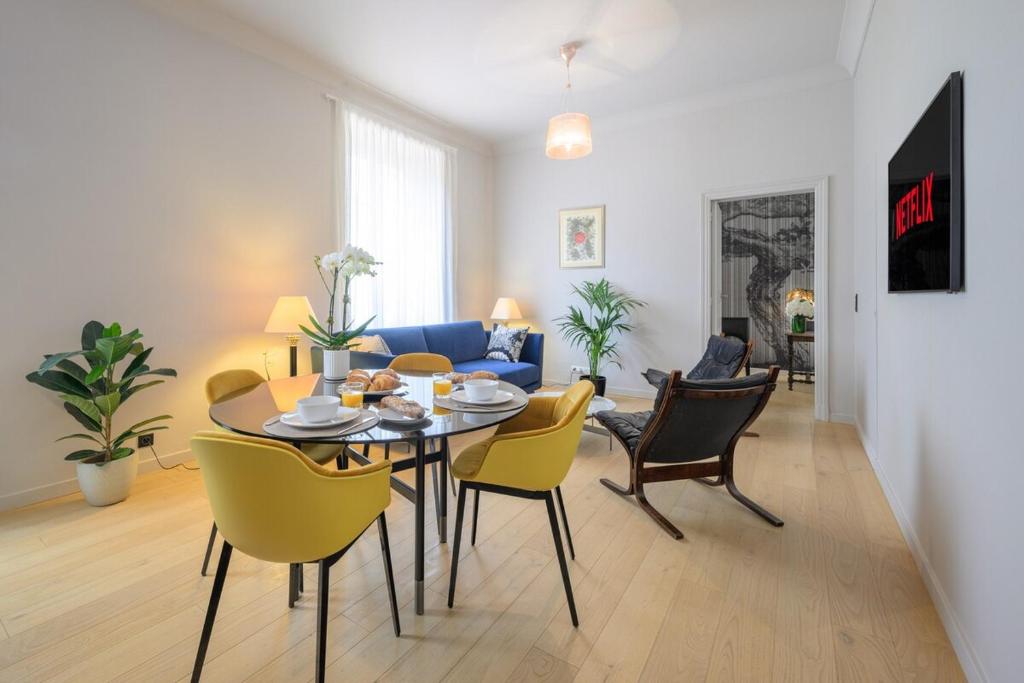 a living room with a table and yellow chairs at Le COQ Impérial - Parking - Spacieux in Menton