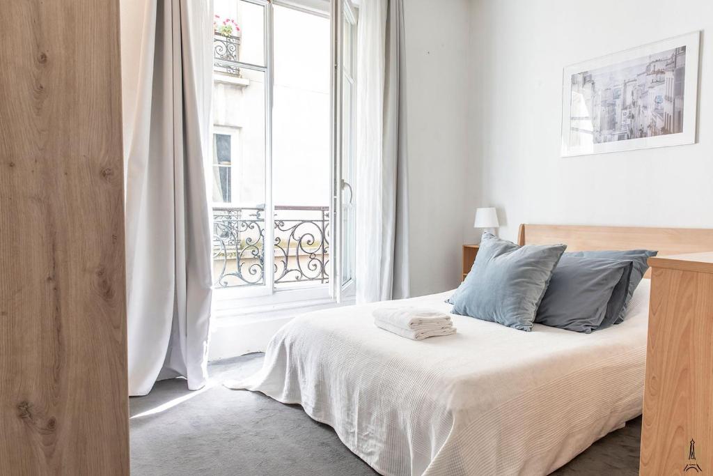 une chambre avec un lit et une grande fenêtre dans l'établissement Montmartre Apartments - Degas, à Paris