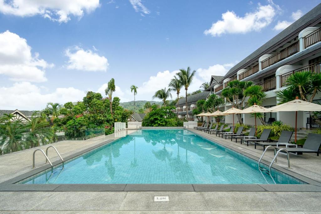 a pool at a hotel with chairs and umbrellas at Andamantra Resort and Villa Phuket - SHA Extra Plus in Patong Beach