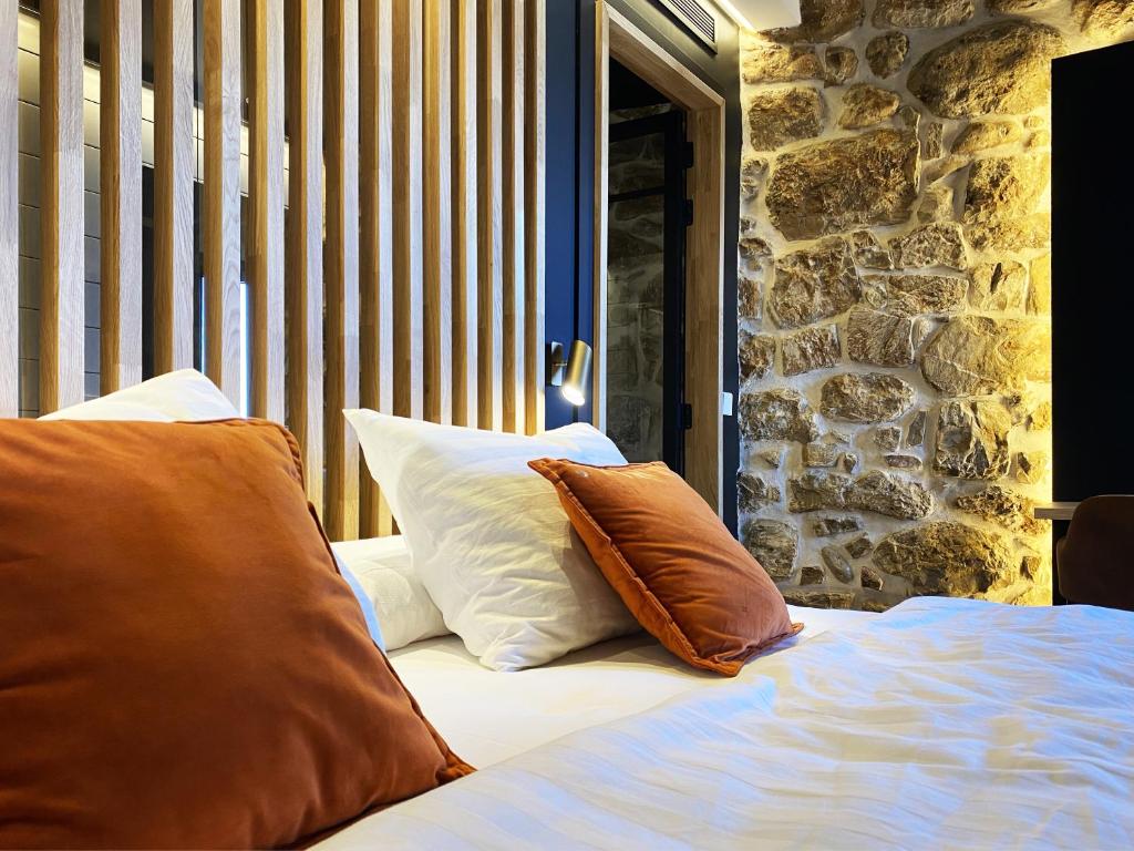 Pou by Seaward Suites Only Adults في فايلاجويوسا: سرير ووسادتين عليه بجانب جدار حجري