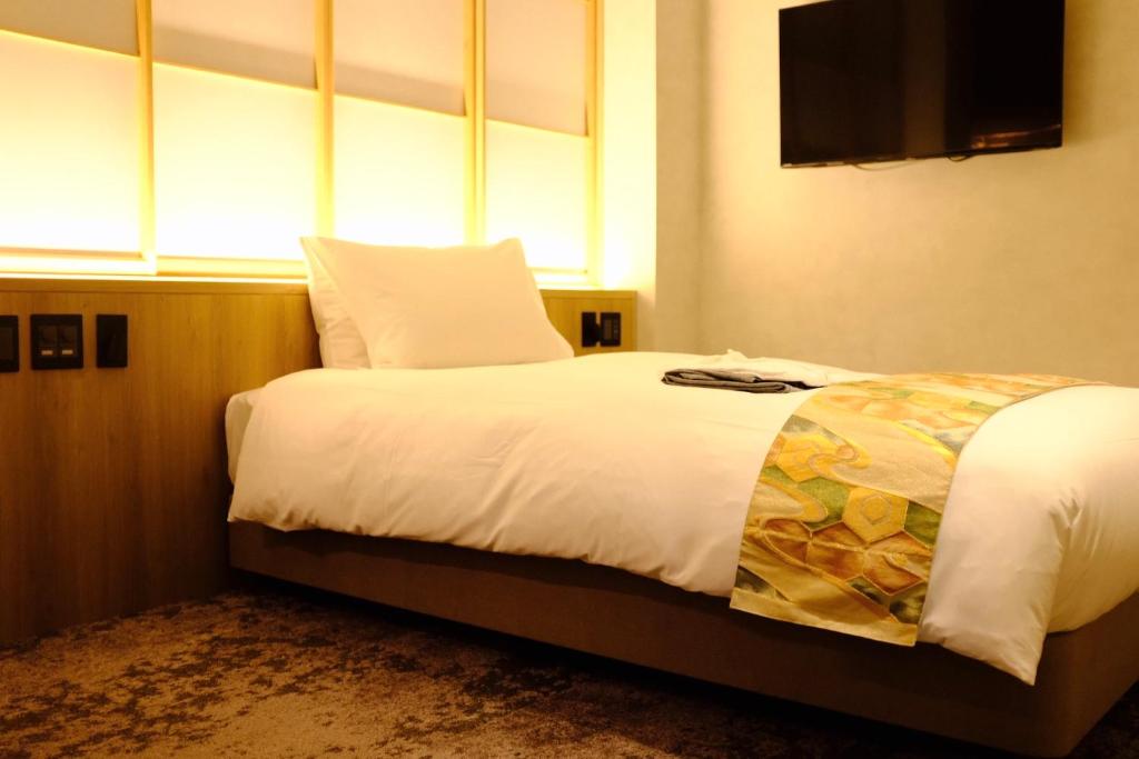 a bedroom with a large bed with a television on the wall at Miru Kyoto Gion in Kyoto