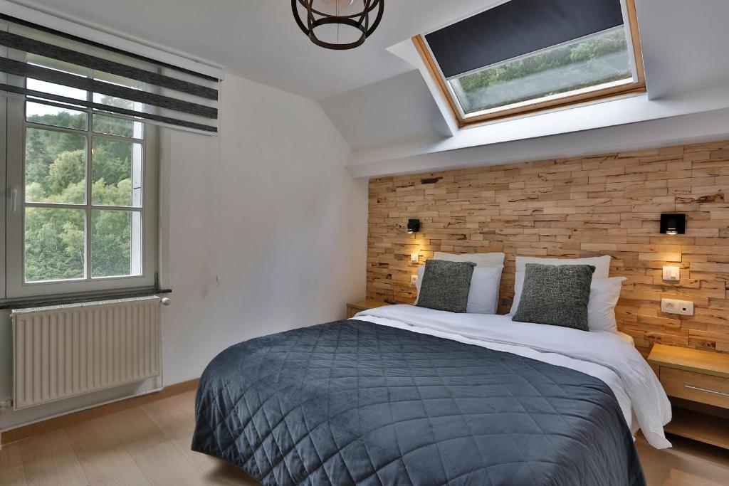 a bedroom with a large bed and two windows at Hotel L'ermitage in Houffalize