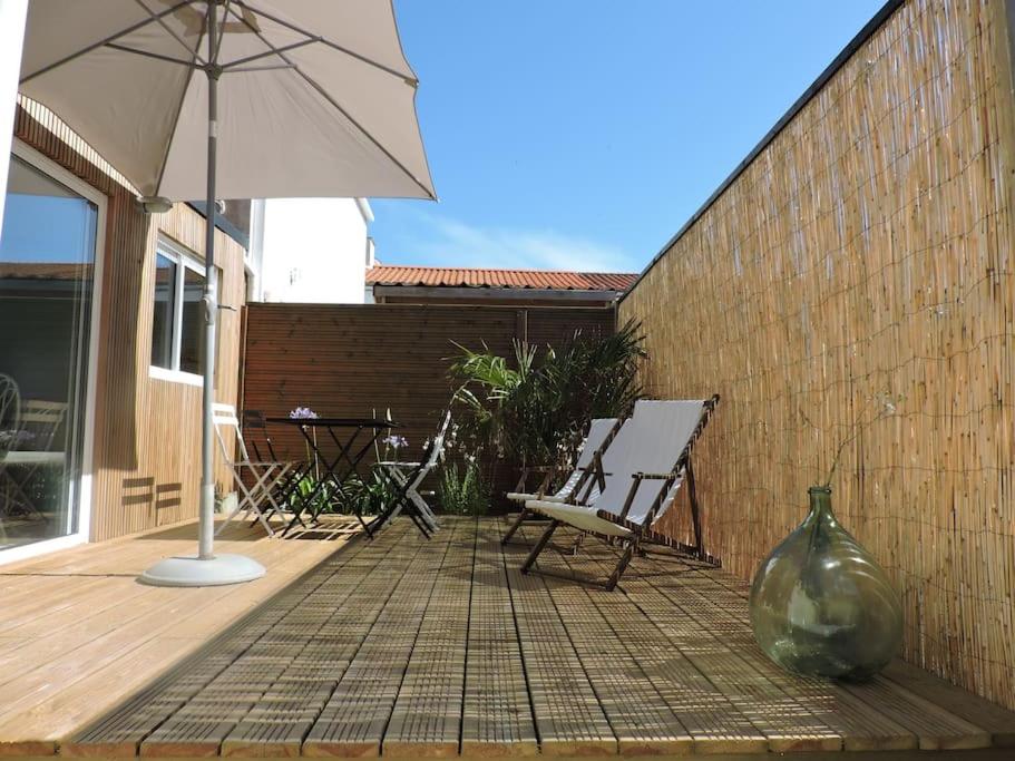 une terrasse avec un parasol, une chaise et un vase dans l'établissement 100 m de la plage, maison de vacances cœur de St Gilles, à Saint-Gilles-Croix-de-Vie