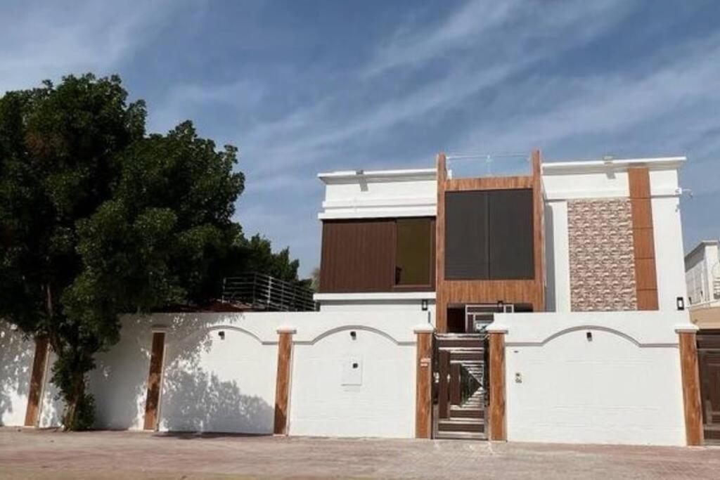 a white building with a fence in front of it at (Anushthan Villa) serviced villa for staycation in Ajman 