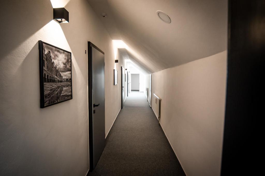 un couloir aux murs blancs et un long couloir avec des lumières dans l'établissement APART Mikeš, à Telč