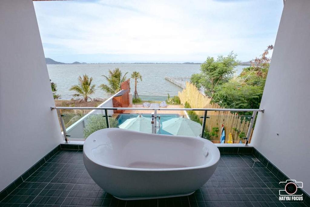 a bath tub on a balcony with a view of the ocean at Touchwarin kohyor pool villa ธัชวารินเกาะยอพูลวิลล่า in Songkhla